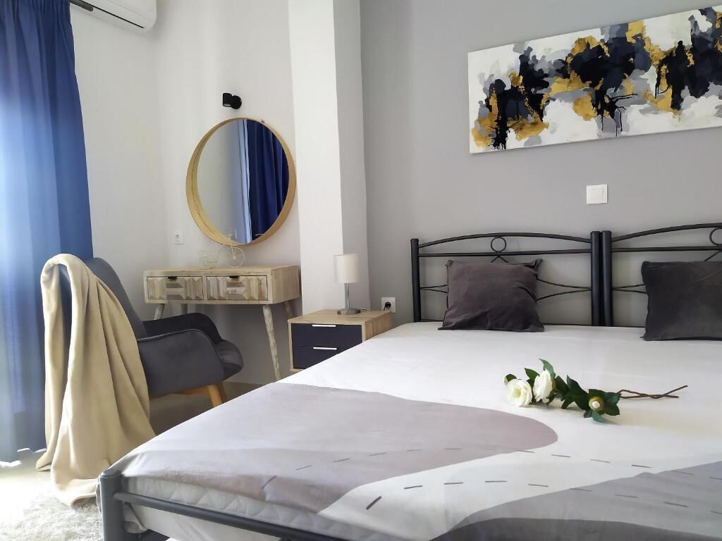 A bedroom with a bed, a bedside table, a mirror, a dresser, and a wall-mounted artwork.