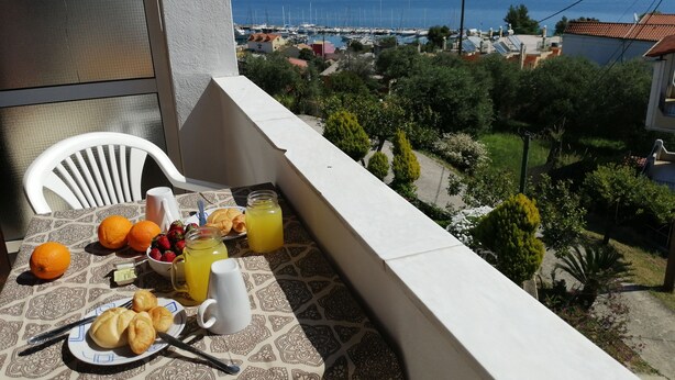 A balcony with a table set for breakfast, including croissants, oranges, and a pitcher of orange juice. - Roza Studios (Corfu)