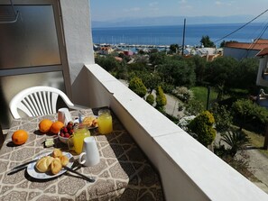 A balcony with a table set for breakfast, including croissants, oranges, and a pitcher of orange juice. - Roza Studios (Corfu)