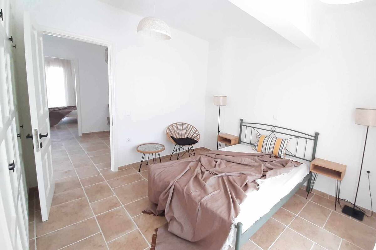 A bedroom with a bed, a chair, a lamp, and a floor lamp.