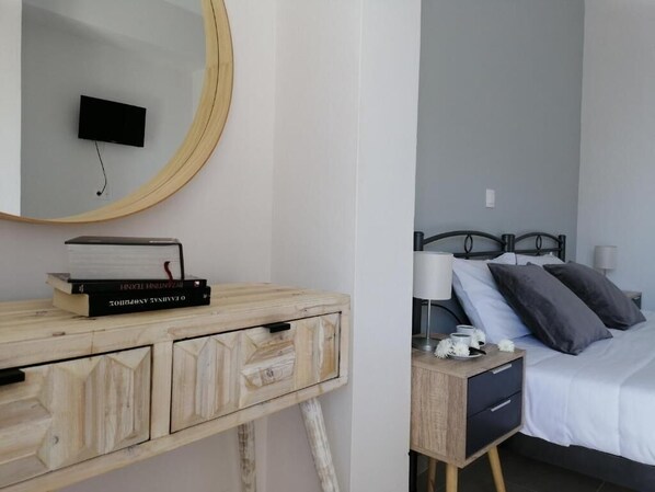 A bedroom with a bed, bedside table, lamp, and a mirror. - Roza Studios (Corfu)