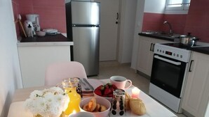 A breakfast setup with a table, a coffee pot, a glass of juice, a bowl of strawberries, a croissant, and a candle. - Roza Studios (Corfu)