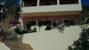 A two-story building with a staircase leading up to a balcony. - Roza Studios (Corfu)