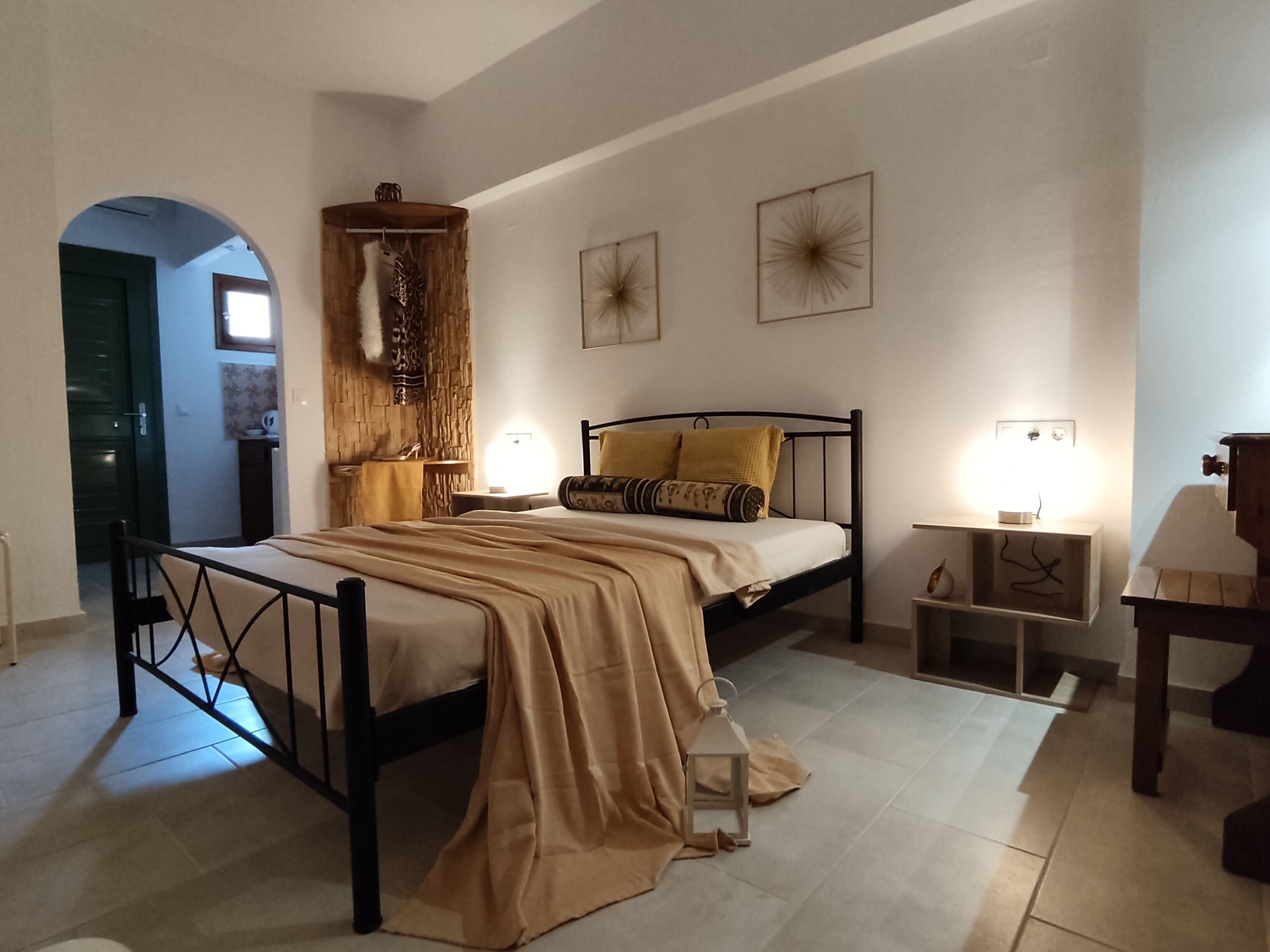 A bedroom with a bed, bedside tables, a lamp, and a wall-mounted shelf.