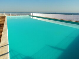 Una piscina al aire libre, sombrillas, sillones reclinables de piscina