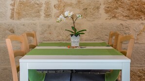 A table with a white tablecloth, green placemat, and a vase with white flowers. - Dimora Grottone (Polignano a Mare)
