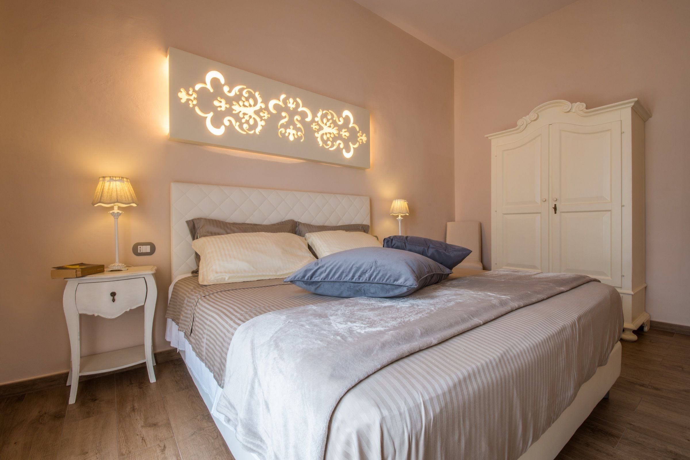 A bedroom with a bed, nightstands, a wall-mounted light fixture, and a wardrobe.