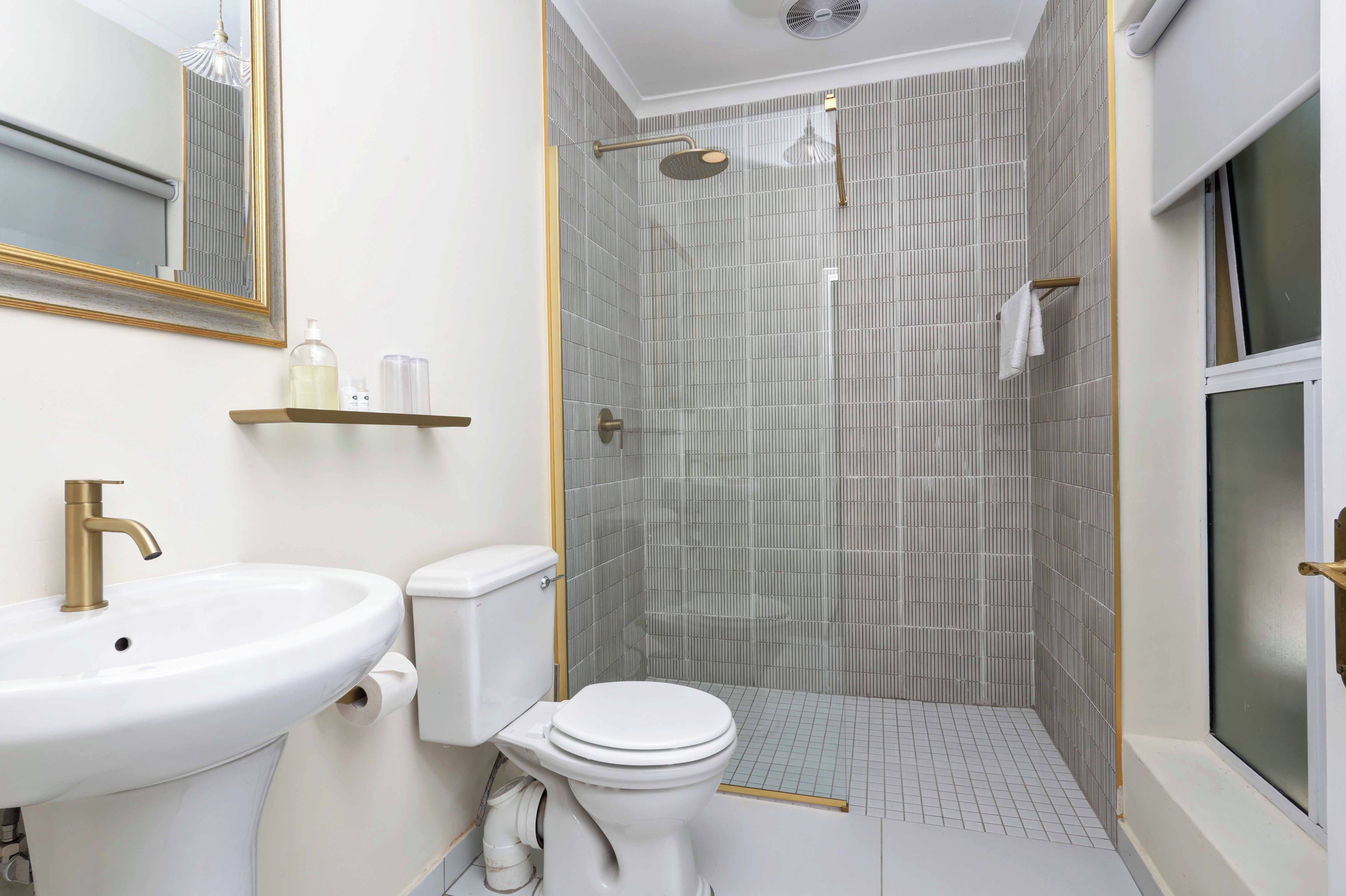 A bathroom with a white sink, toilet, and shower area.