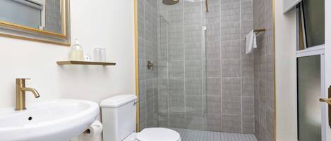 A bathroom with a white sink, toilet, and shower area.