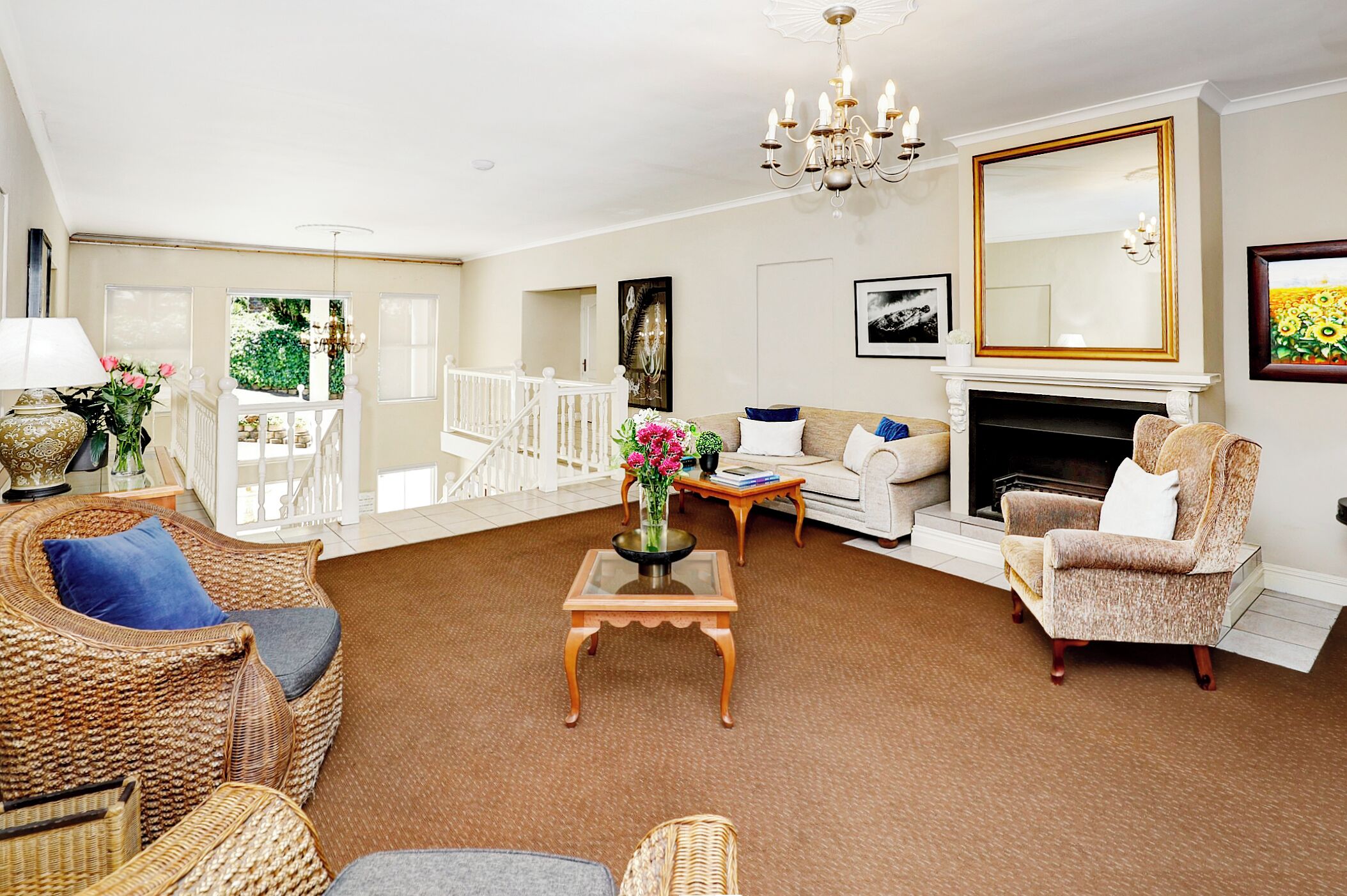 A spacious living room with a fireplace, wicker furniture, and a large mirror.