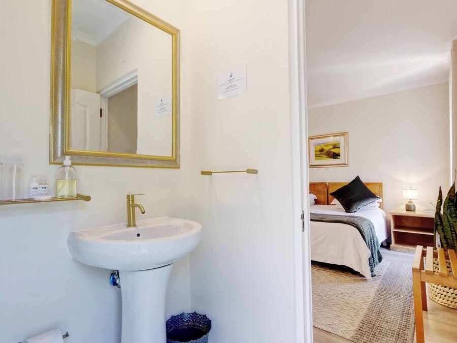 Un baño de hotel con lavamanos, espejo y artículos de aseo.