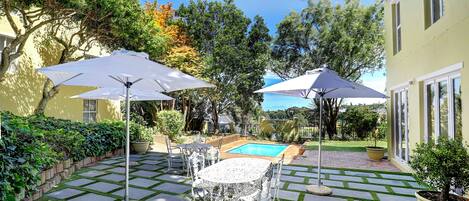 A patio area with a pool, outdoor furniture, and potted plants.