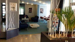 Un moderno vestíbulo de hotel con recepción, zona de estar y comedor.