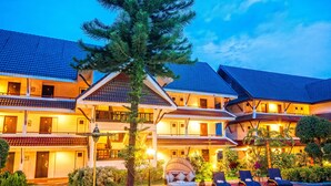 A hotel with a swimming pool, outdoor seating, and a well-lit facade. - Nak Nakara Hotel (Chiang Rai)