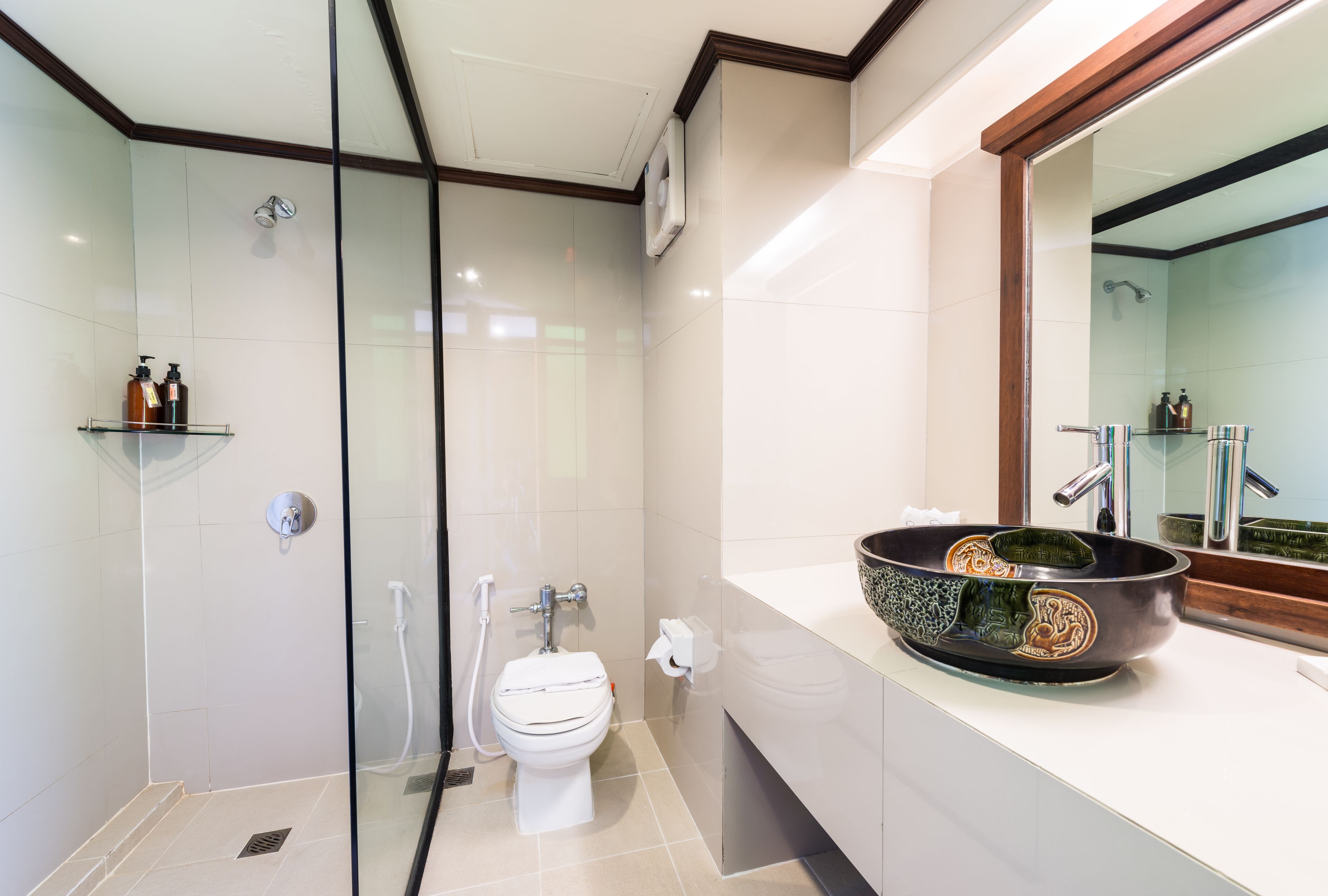 Un baño moderno con ducha acristalada, inodoro blanco y un lavabo grande con diseño decorativo.