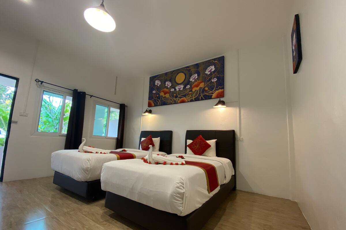 Habitación de hotel con dos camas, un cuadro grande encima y una ventana con cortinas.
