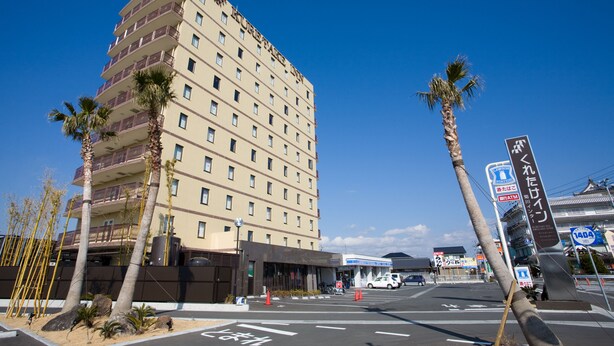 Un hôtel à plusieurs étages doté de balcons, de palmiers et surplombant un ciel d’un bleu limpide.