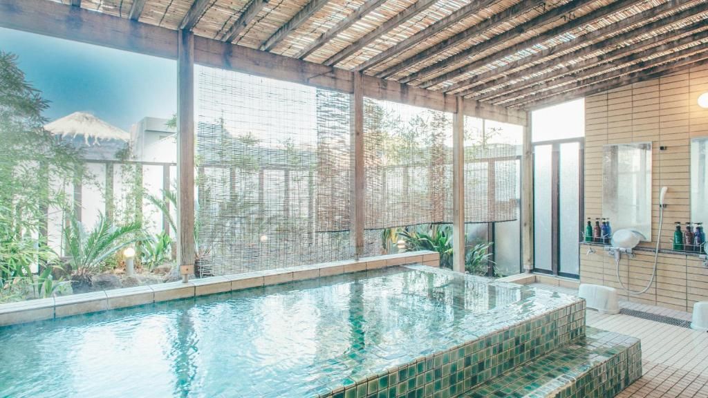 A swimming pool with a tiled edge, surrounded by a covered area with a wooden ceiling.