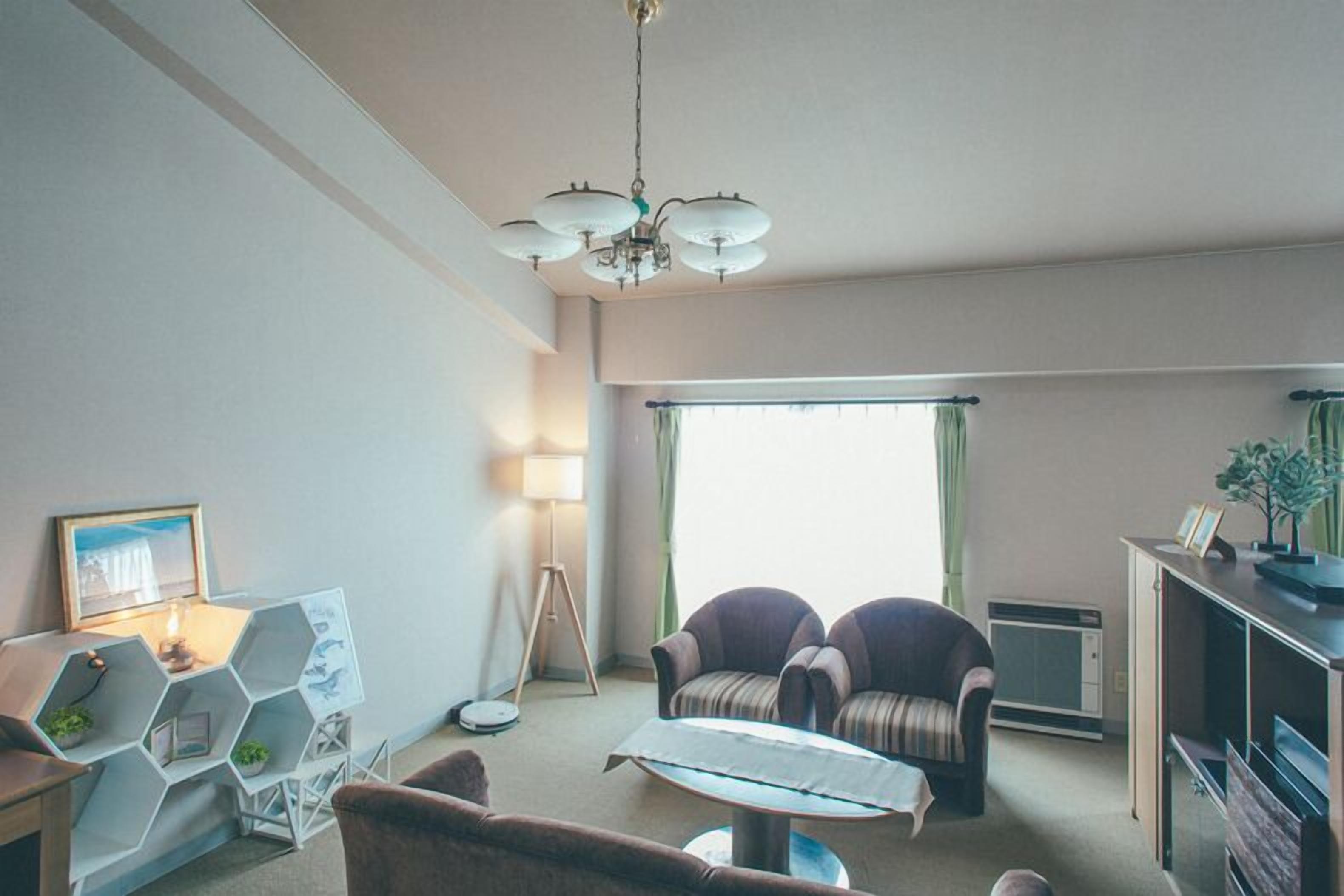 Un salon comprenant un canapé, une table basse, une lampe, un meuble de rangement hexagonal et une grande fenêtre avec des rideaux.