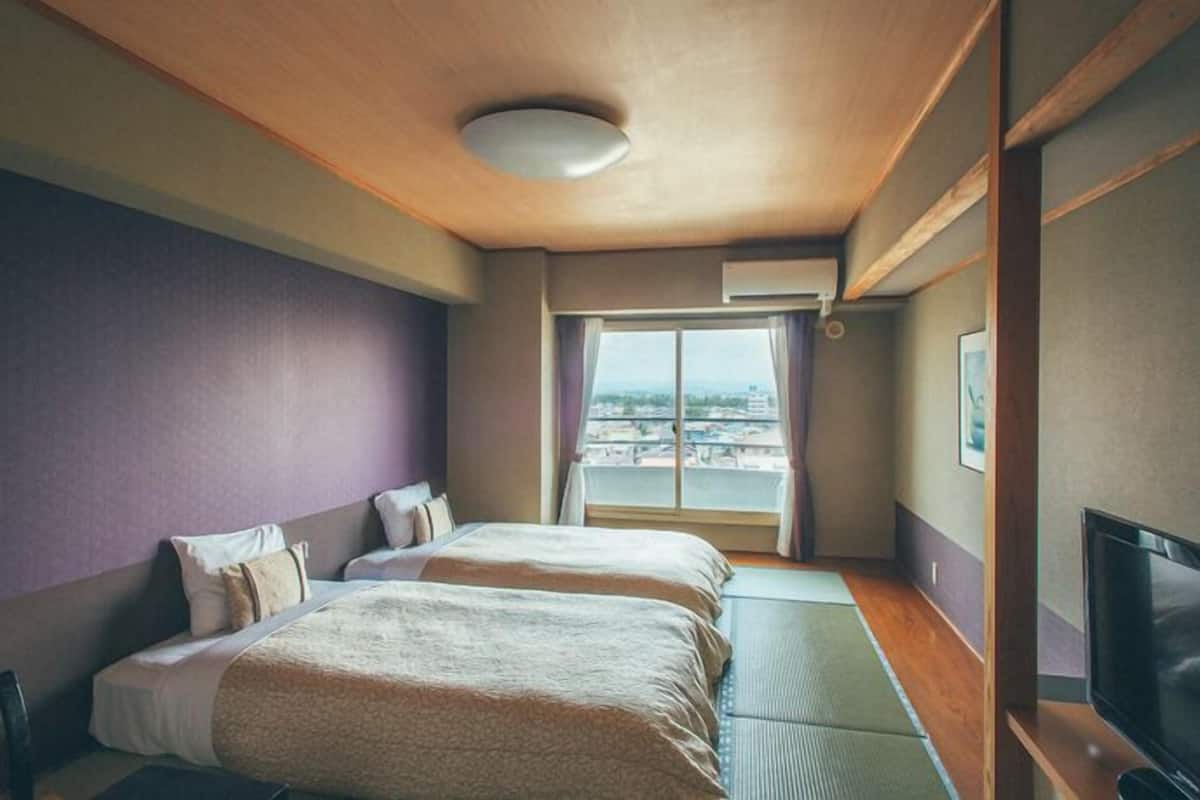 Ein Hotelzimmer mit zwei Betten, einem großen Fenster mit Blick, einem Flachbildfernseher und einer Deckenleuchte.