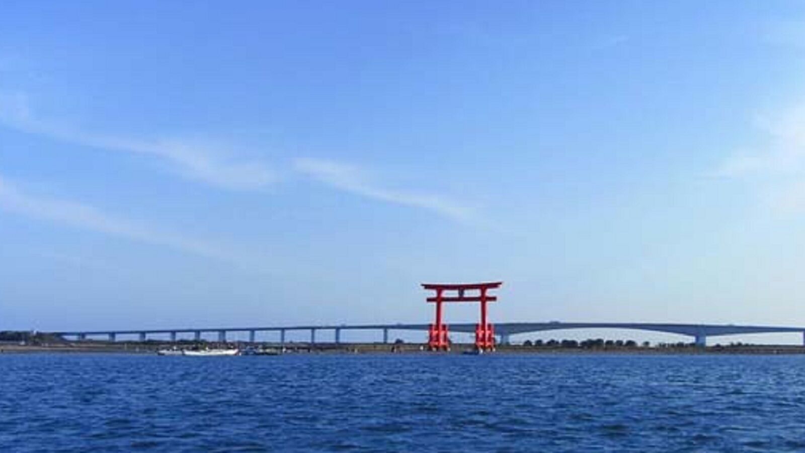 Un pont avec un portail torii rouge en premier plan.