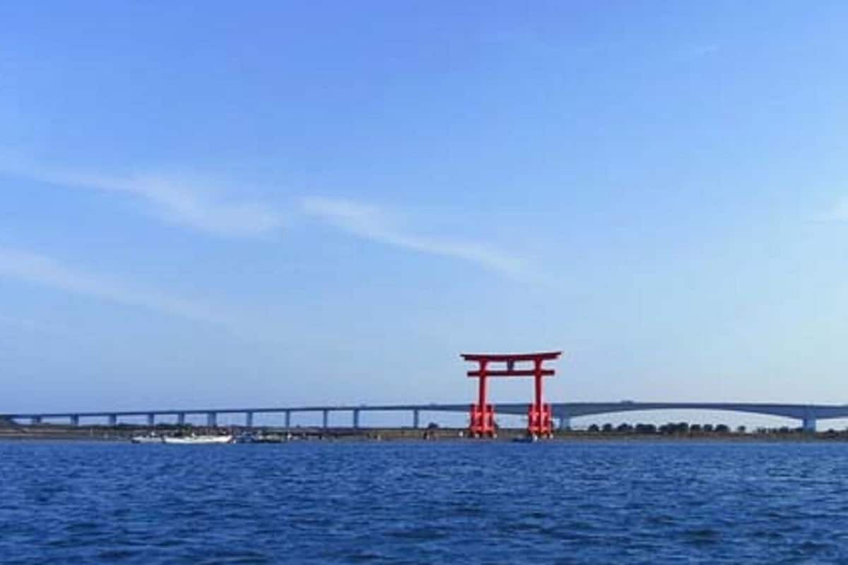 Eine Brücke mit einem roten Torii-Tor im Vordergrund.