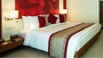 Een hotelkamer met een groot bed, twee nachtkastjes en een hoofdbord met een rood patroon.