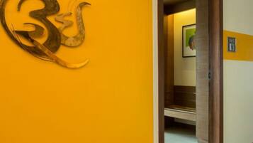 A hallway with a large, abstract golden sculpture on the wall and a door leading to another room.