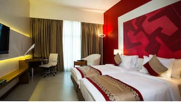 Ein Hotelzimmer mit einem großen Bett, einem Schreibtisch, einem Stuhl und einem Fernseher.