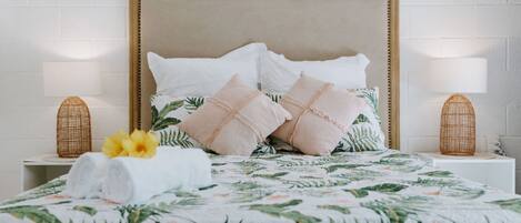 A neatly made bed with a floral bedspread, two bedside lamps, and a woven basket on each nightstand.