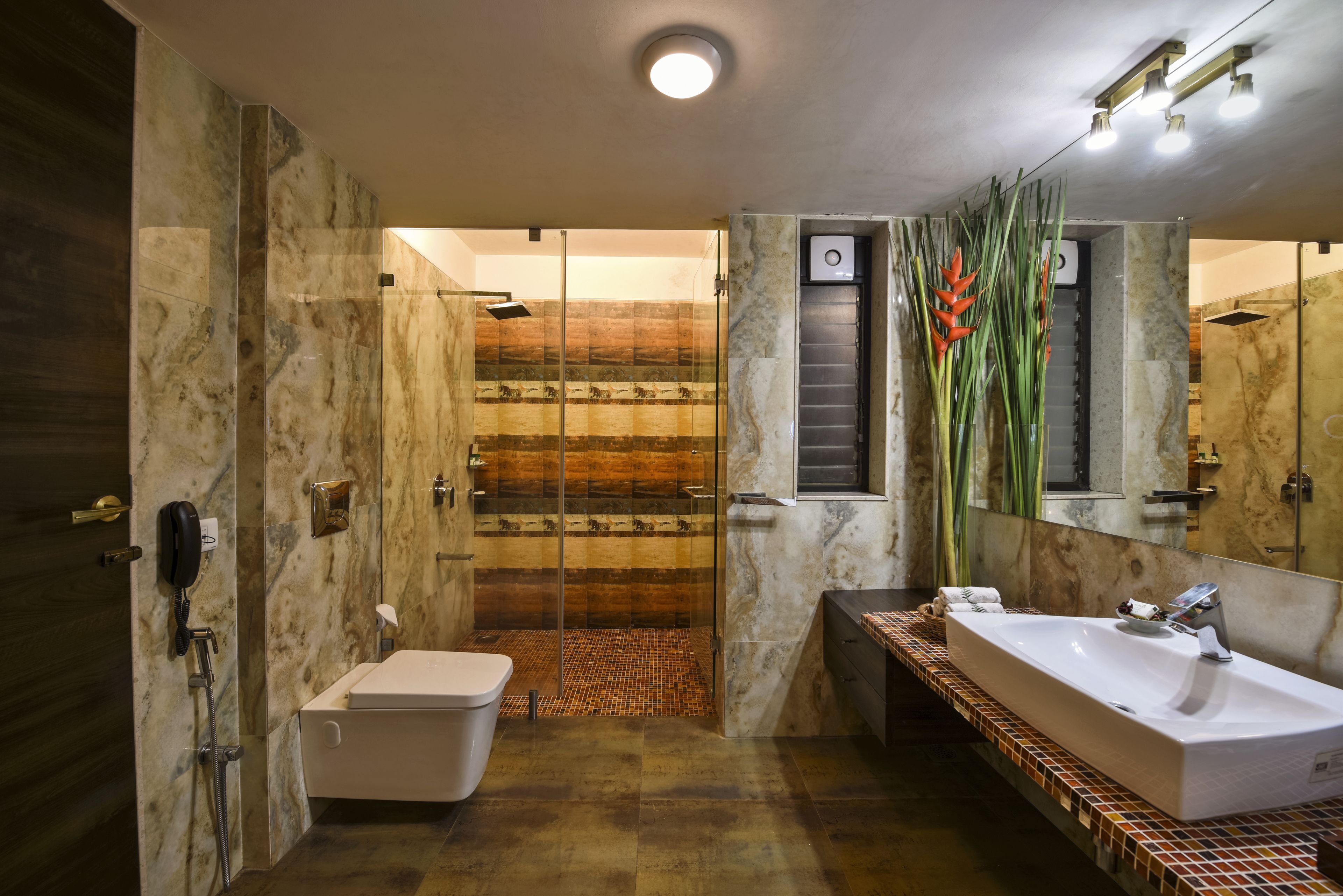 A modern bathroom with a glass-enclosed shower, a large sink, and a mirror.