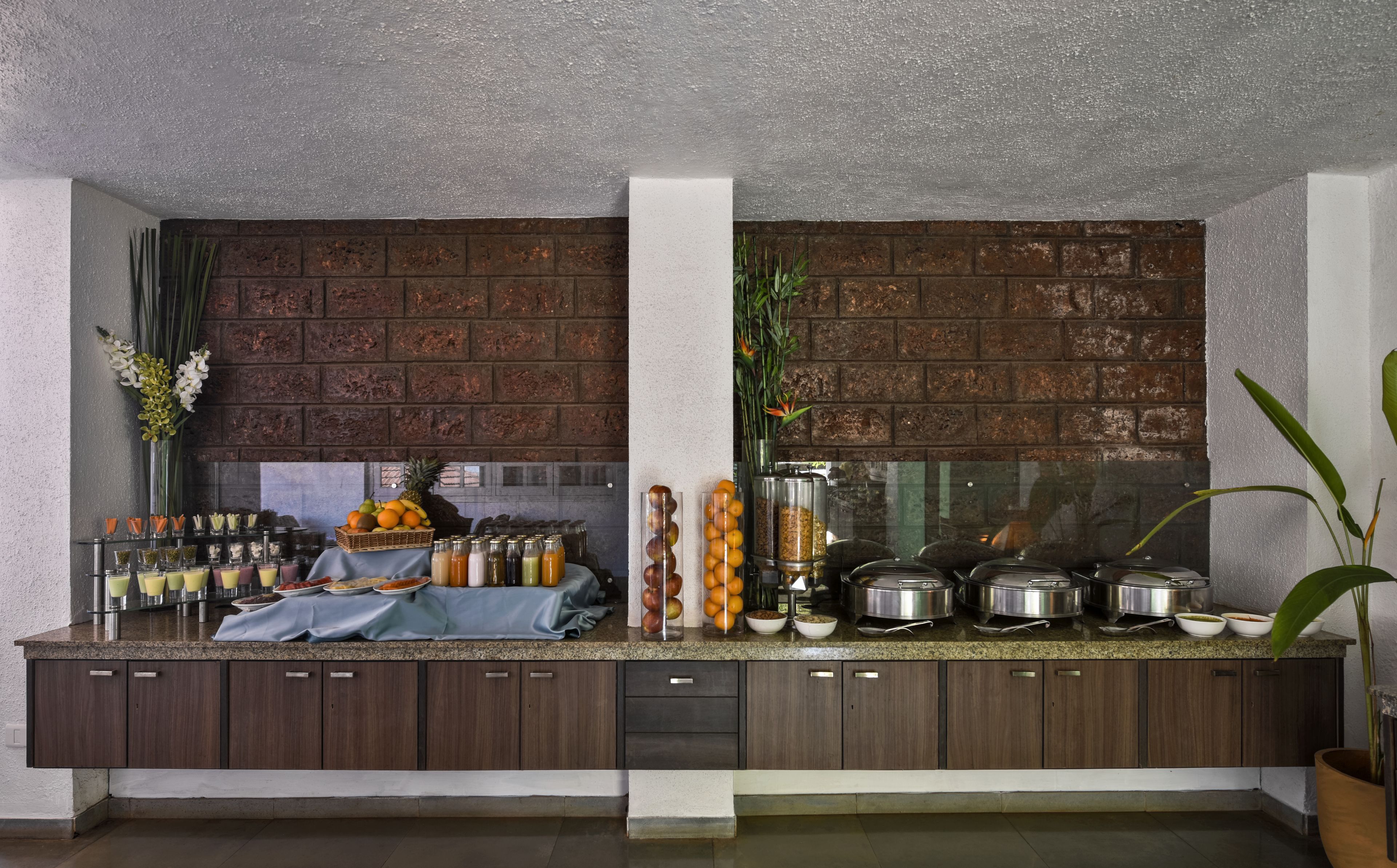 A kitchen with a brick wall, a buffet setup with various food items, and a large window.