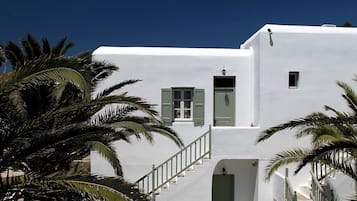 A white building with a staircase, palm trees, and a stone pathway.