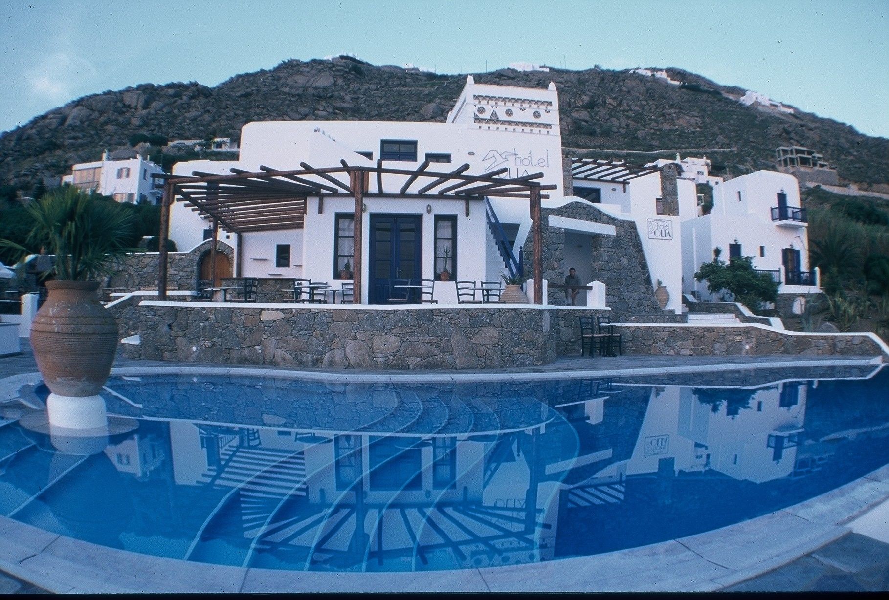 Um hotel com piscina, área de estar ao ar livre e montanhas ao fundo.