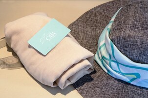 Una toalla beige doblada con pulcritud y una etiqueta azul claro sobre una superficie gris con textura.