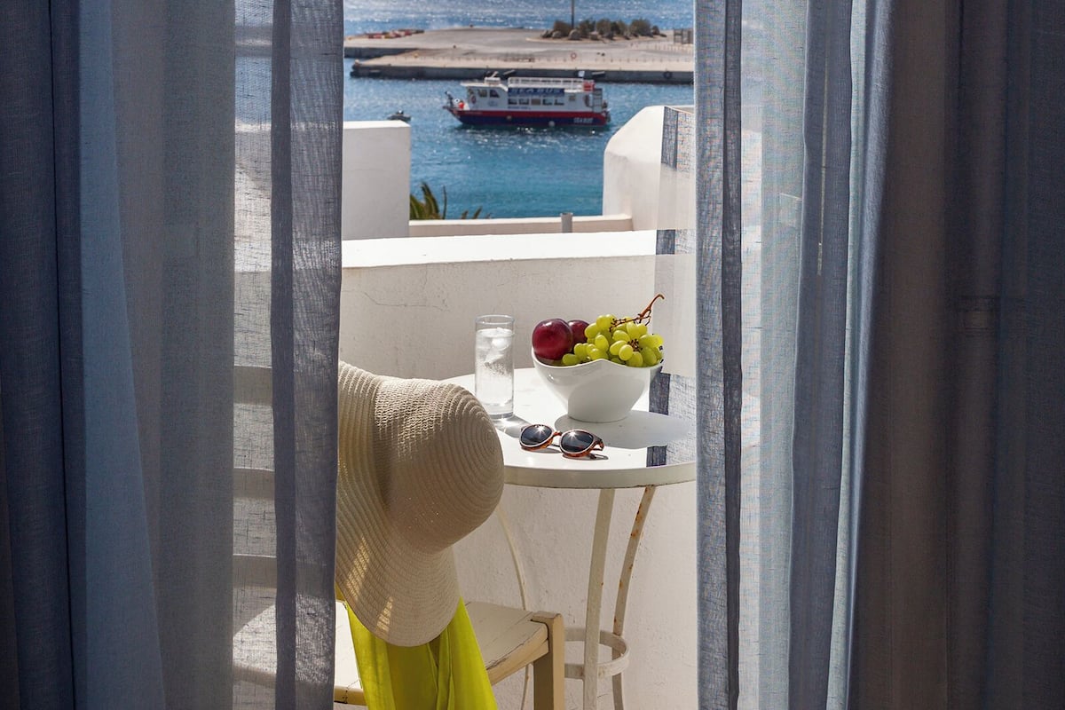 A balcony with a table, a chair, and a view of the sea and boats.
