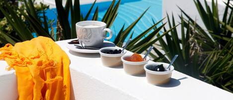 A poolside setting with a white table, a white cup, and three small bowls with food items.