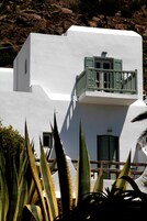 Un edificio blanco con balcón, rodeado de plantas.