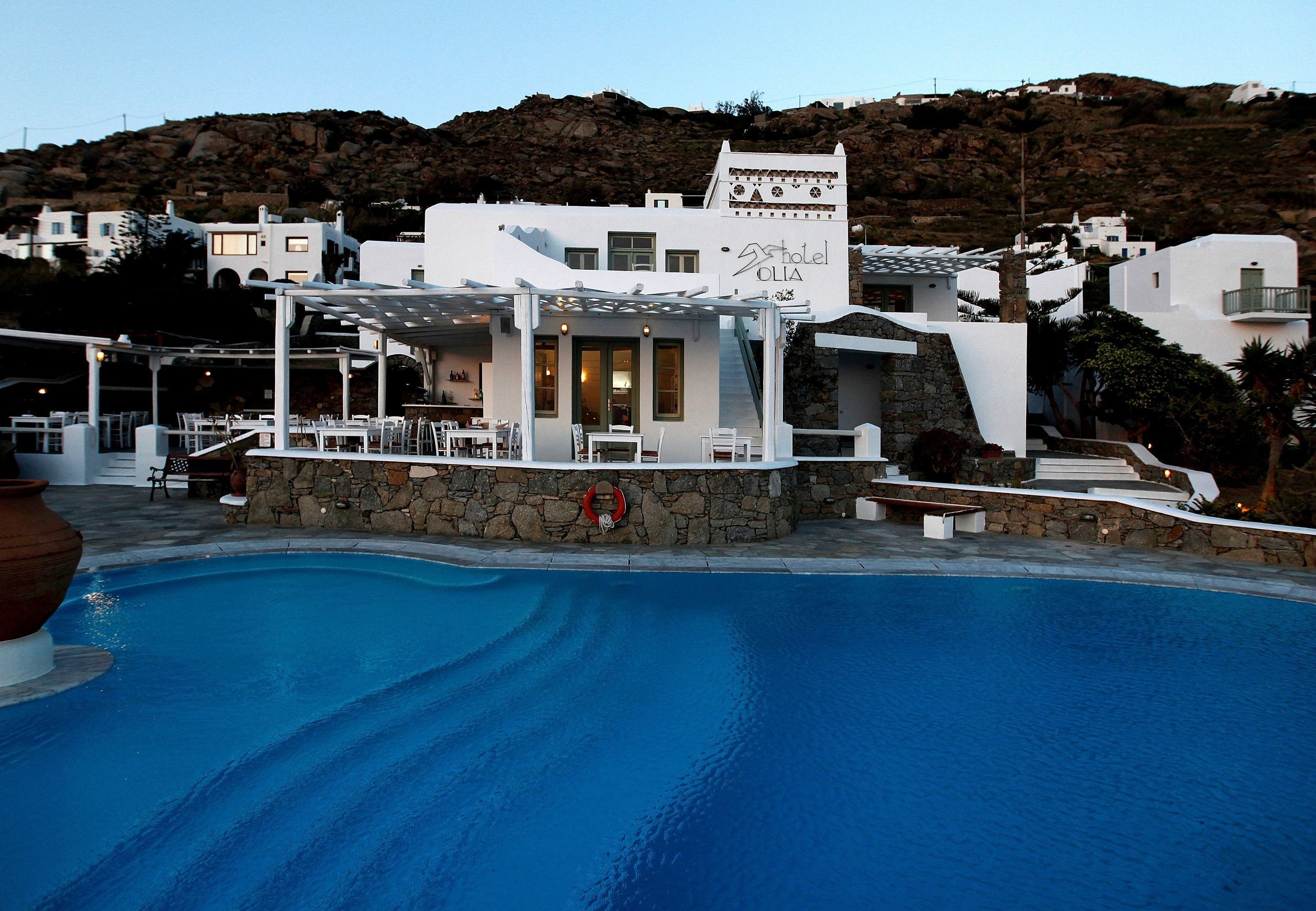 Un hotel con piscina, paredes de piedra y vistas del paisaje circundante.