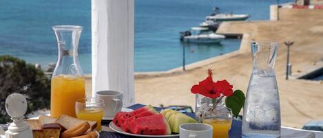 A breakfast table with a view of the sea, including boats and a sandy beach.
