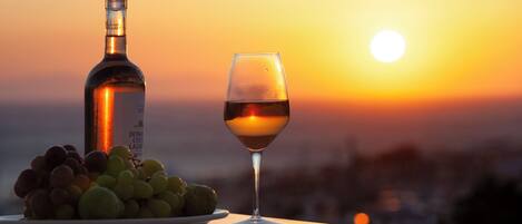 Une bouteille de vin et un verre de vin sur une table, avec une vue sur le coucher de soleil.