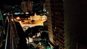 A nighttime cityscape with illuminated buildings, a prominent central structure, and a road with palm trees. - Amazonas Palace Hotel Belo Horizonte - Avenida Amazonas (Belo Horizonte)