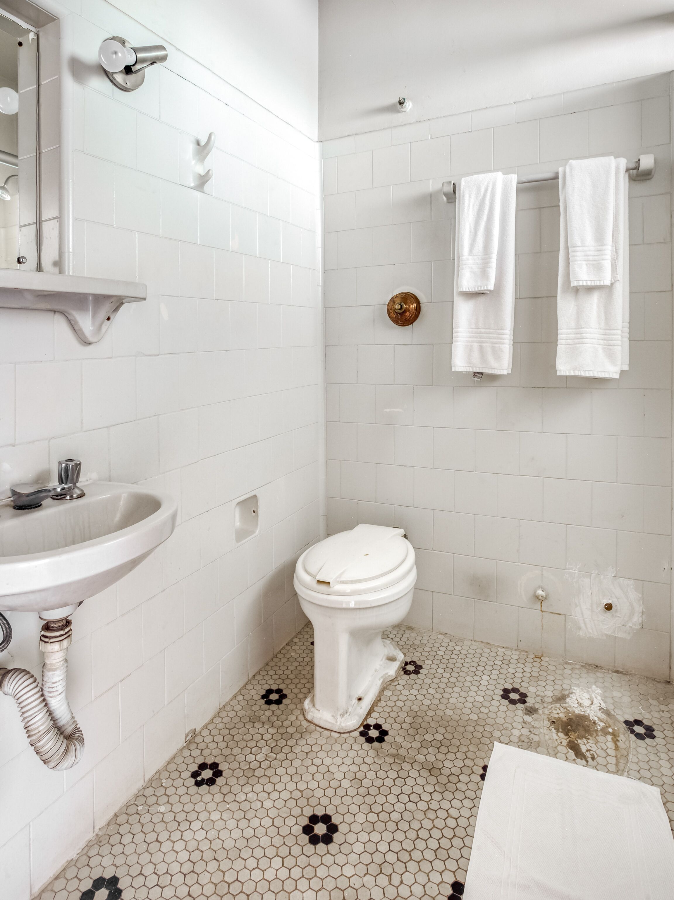 A bathroom with white tiles, a sink, a toilet, and a towel rack.
