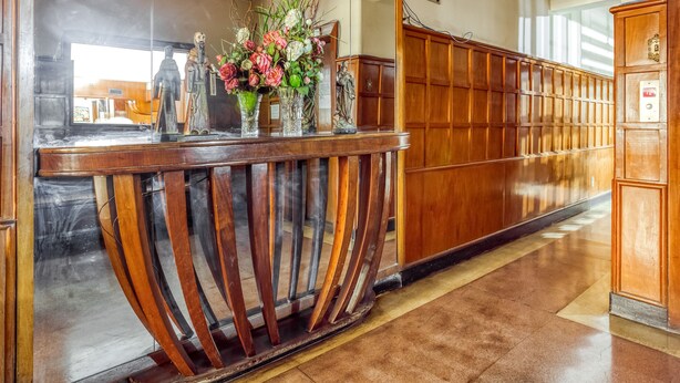 A reception desk with a wooden finish, a mirror, and a sign indicating a restaurant/bar. - Amazonas Palace Hotel Belo Horizonte - Avenida Amazonas (Belo Horizonte)