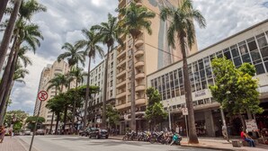 A street with tall buildings, palm trees, and parked motorcycles. - Amazonas Palace Hotel Belo Horizonte - Avenida Amazonas (Belo Horizonte)