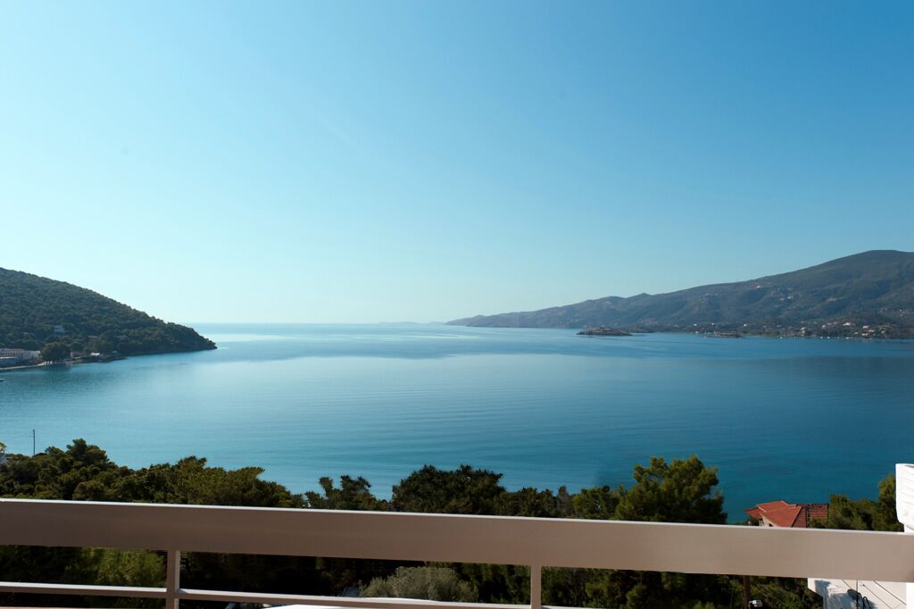 Une vue sur la côte, avec un ciel dégagé, une mer calme et des collines à l’horizon.