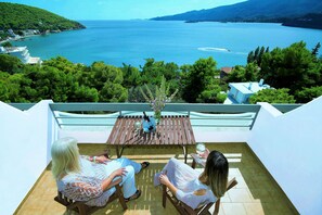 A terrace with a view of a lake, surrounded by greenery. - Panorama Apartments (Poros)