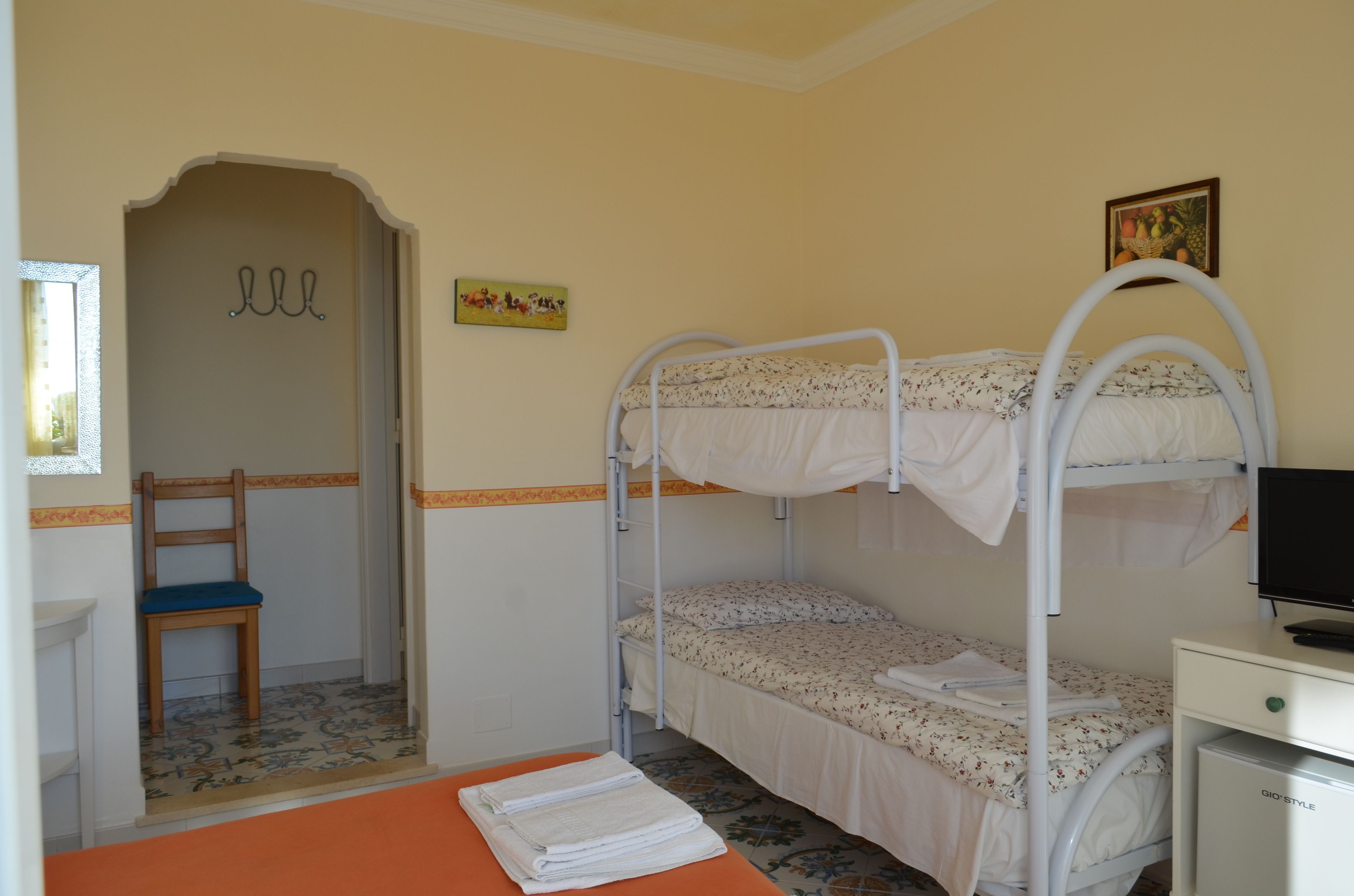 Habitación con literas, un escritorio, una silla, una mesita pequeña y un cuadro en la pared.