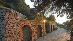 A stone bridge with arches, a paved path, and a railing. - Alle Ginestre B&B (Anacapri)