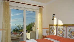 A hotel room with a bed, a chair, a table, and a view of the outdoors. - Alle Ginestre B&B (Anacapri)